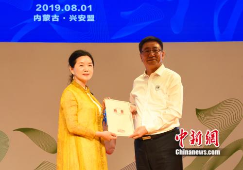 图为内蒙古自治区党委宣传部部长白玉刚为“苏绣皇后”姚建萍颁发聘书,聘请她为蒙古族刺绣传承创新协会名誉理事长。张玮 摄 点击进入下一页
