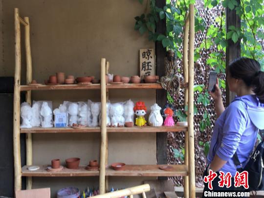 图为月牙泉小镇“敦煌彩陶”门口晾胚区吸引当地人拍照留念。 张婧 摄 图为月牙泉小镇“敦煌彩陶”门口晾胚区吸引当地人拍照留念。 张婧 摄
